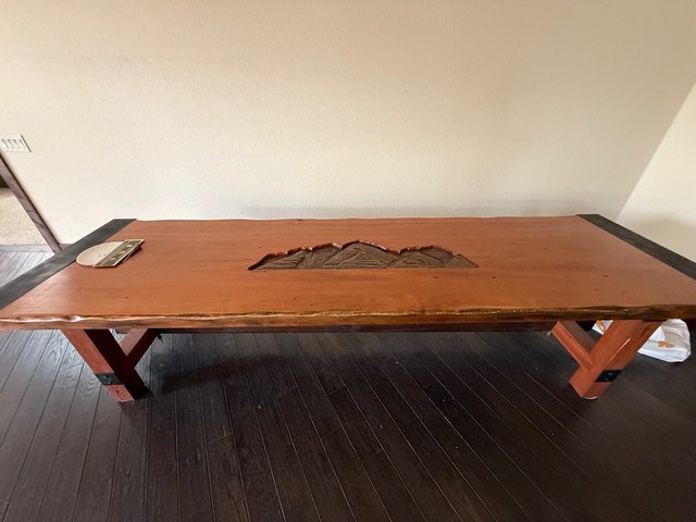Long live-edge wooden table with a carved mountain inlay