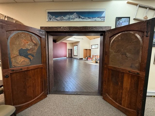 The carved doors open onto the gallery hall with dark wood floors